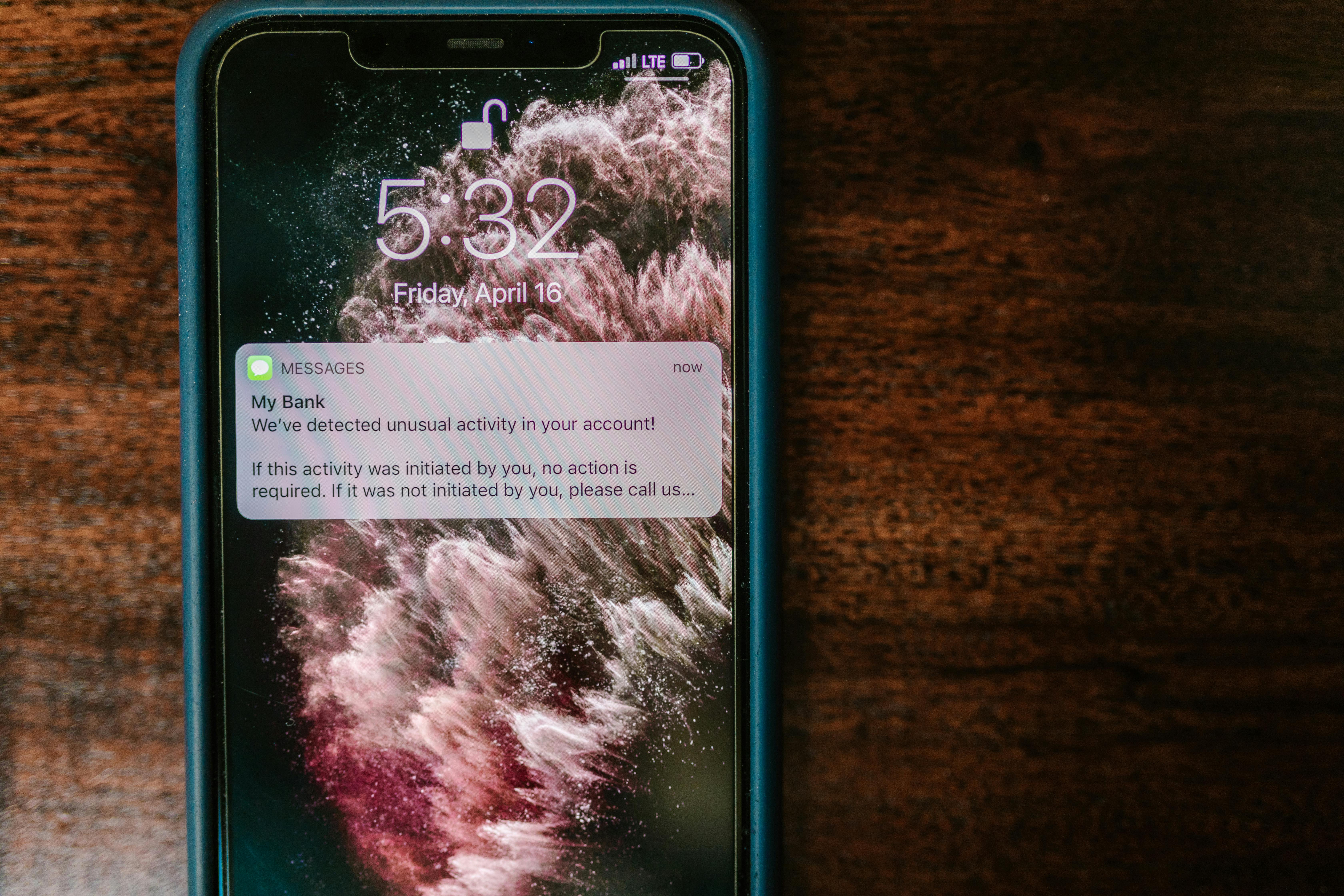 Photos of an iPhone on the table with a text alert from "My Bank" that says "We've detected unusual activity in your account" to showcase how you can help protect your financial accounts by setting up alerts.